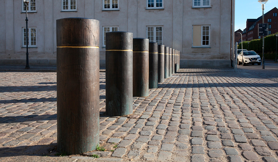 Terrorsikringspullerter integreret i den historiske belægning ved Amalienborg med balance mellem køretøjssikring, offentlig adgang og bydesign.