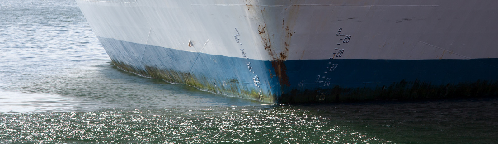 Nærbillede af skibsskrog i vand, der illustrerer maritim sikkerhed, skibskonstruktion og brandtest til marine anvendelser.