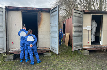 Brændte containere bliver undersøge at brandundersøgere. 