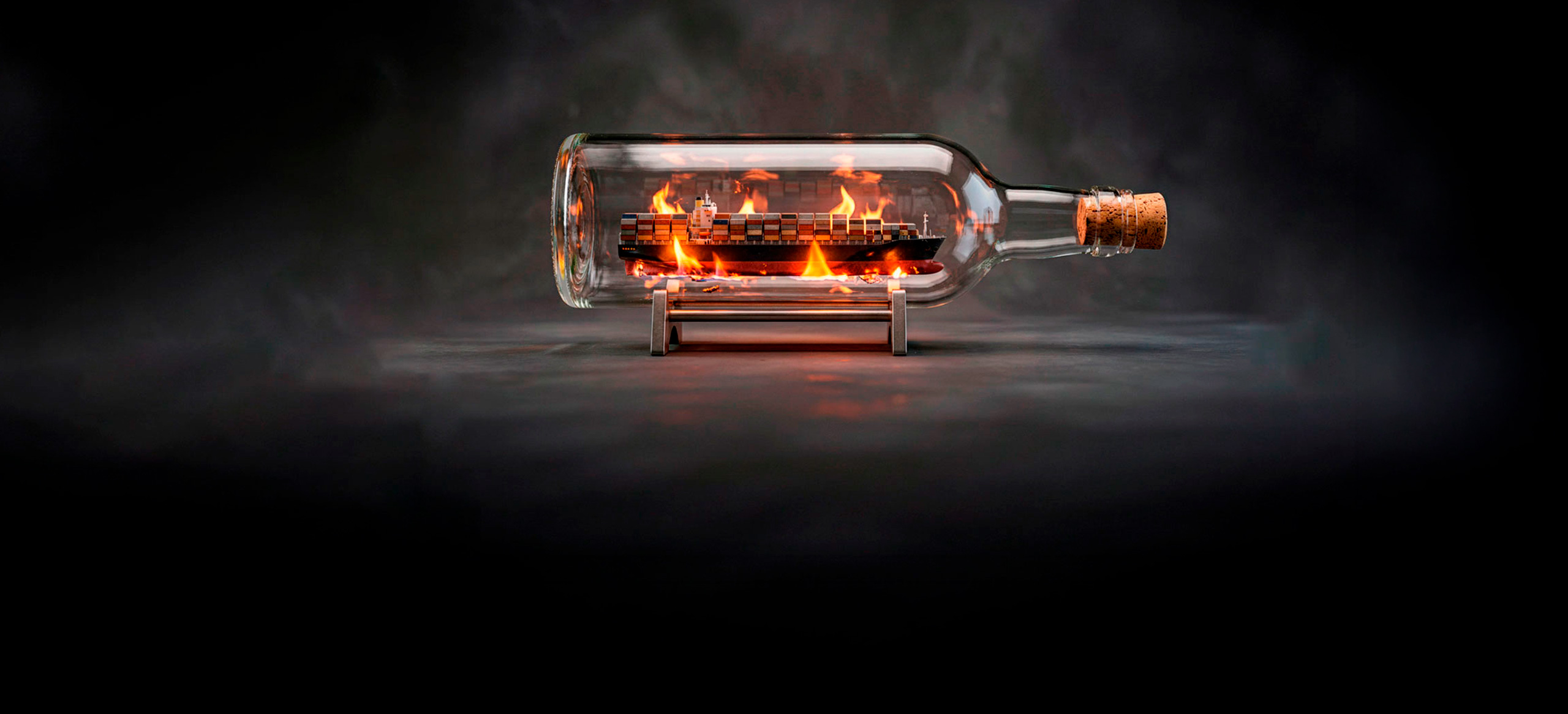 Container ship inside a glass bottle surrounded by flames and smoke.