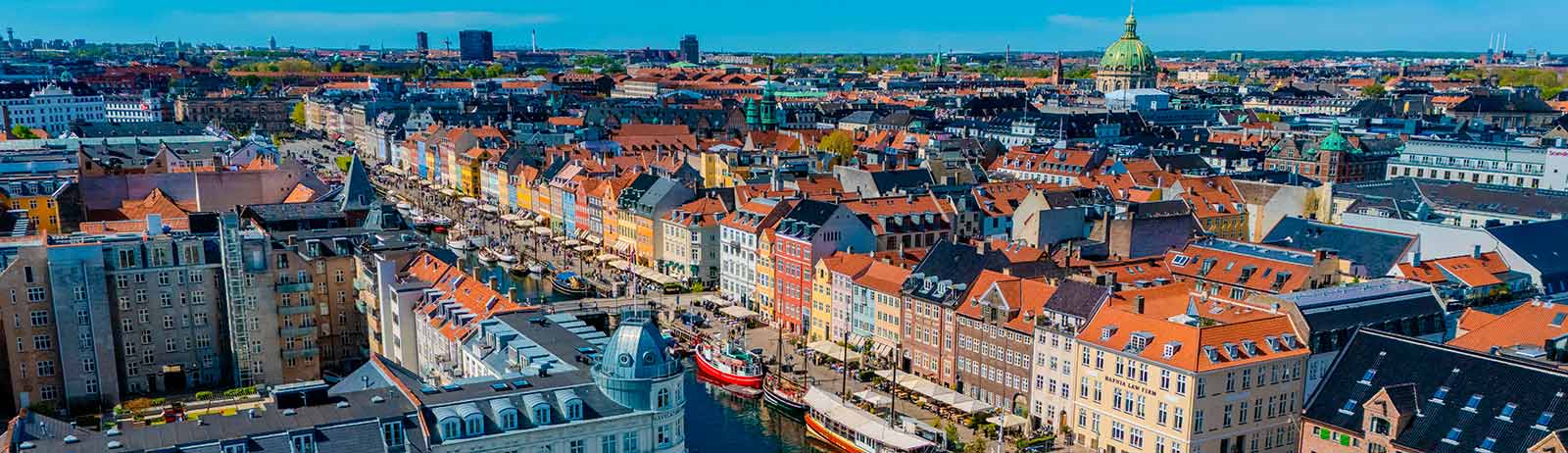 Luftfoto af Nyhavn og Københavns centrum med farverige bygninger og både i kanalen.