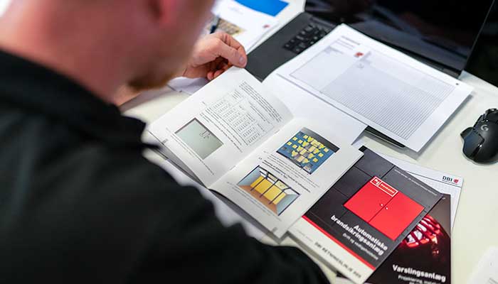 Brandteknisk dokumentation og kontrolmateriale på et skrivebord