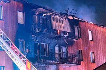 Brandskadet træfacade med svært beskadigede altaner og tagkonstruktion i Upplands-Bro.