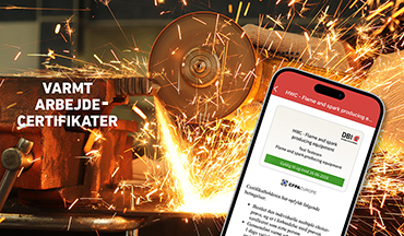 Varmt arbejde-certifikat vist på en mobiltelefon foran en vinkelsliber med gnister.