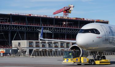 Et fly taxier i Københavns Lufthavn og i baggrund ser man byggeriet i gang af udvidelsen af lufthavnen.