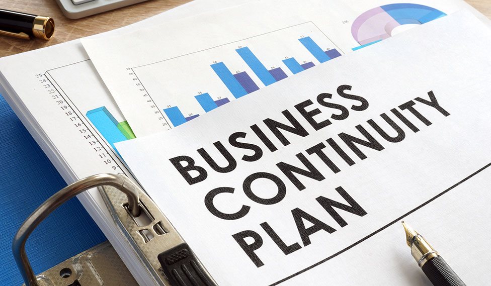 Business continuity plan står skrevet på et stykke papir der ligger over et søjlediagram.