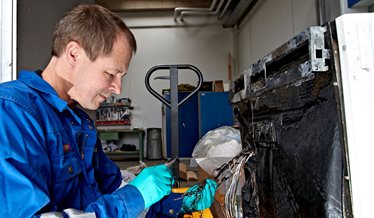 En brandundersøger kigger på en brændt opvaskemaskine.