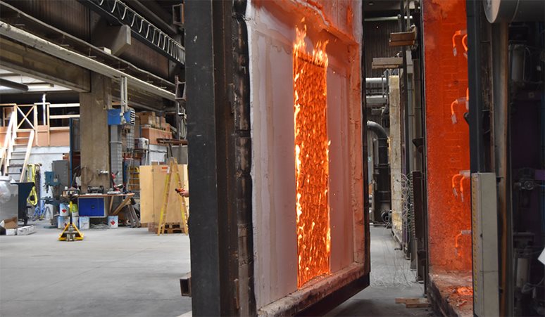 En branddør er blevet brandtestet, og løftes nu væk fra ovnen.