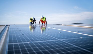 To hådværkere arbejder på et tag med solceller