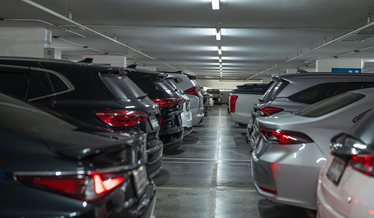 Tæt parkerede biler i et indendørs parkeringsanlæg med lavt loft.